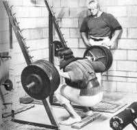 Arnold squatting, Dave looking on.